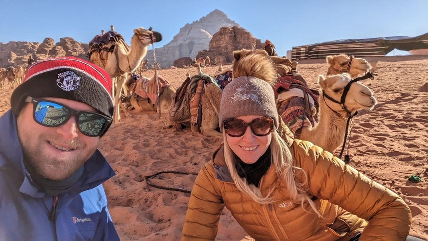 Couple posing with camels and a desert background.