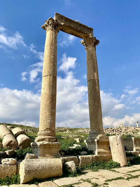 Two ancient stone columns with rolling hills in the distance.