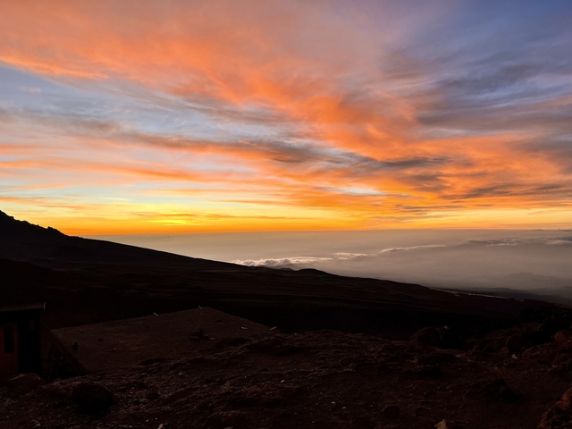 Vibrant sunset over mountain peaks with a broad sky.