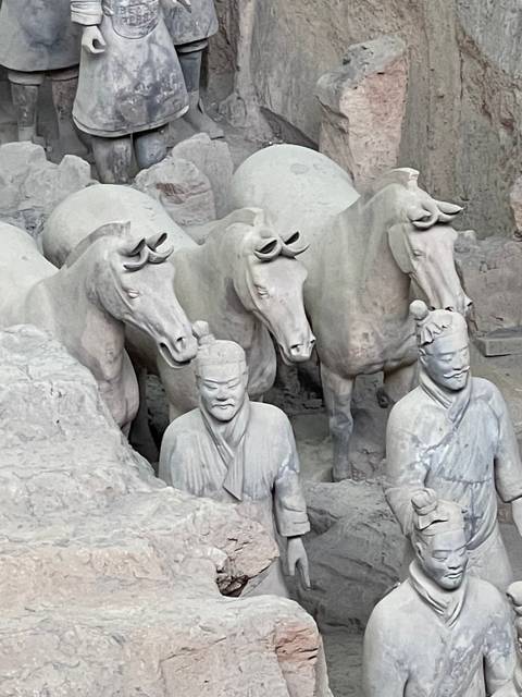 A display of ancient stone sculptures and horses.