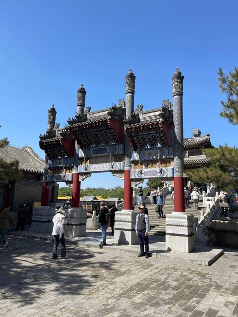       A traditional Chinese gate with tourists around.
  