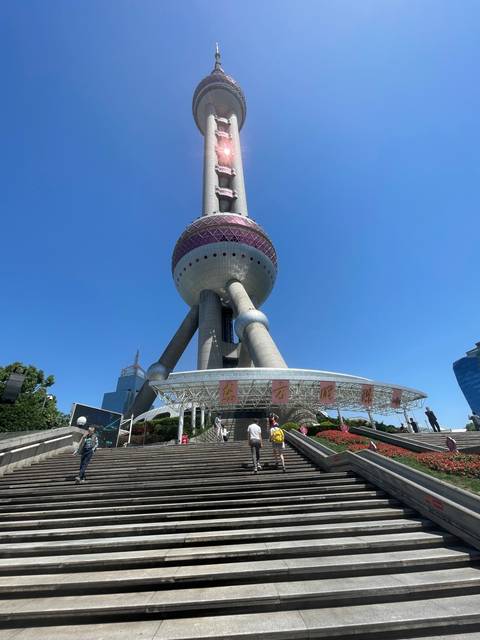 A modern city view with a tall tower and people walking.