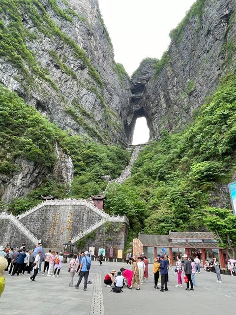 A large natural arch with people walking around.