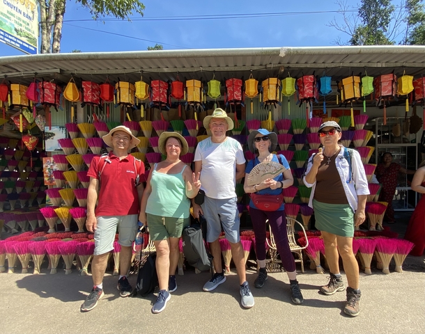 Group of five people posing in front of colorful brooms