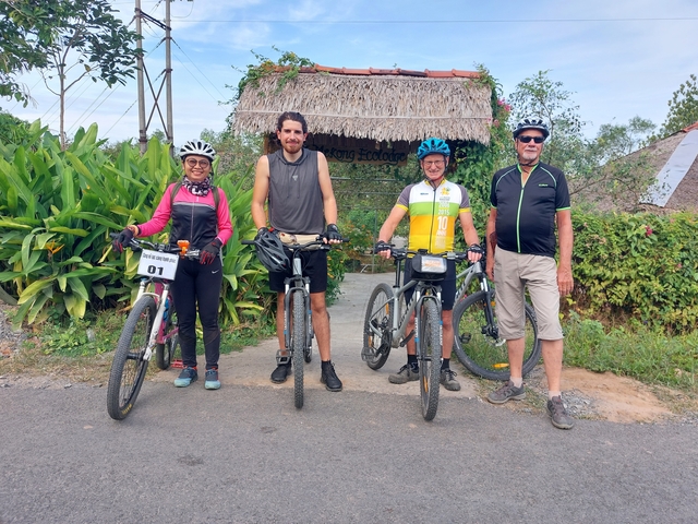 Group of cyclists posing with bicycles in front of a hut