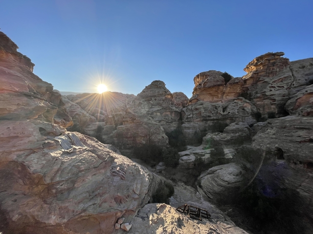 Sun setting over a rocky desert landscape.
