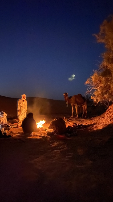 People gathered around a campfire in the desert.