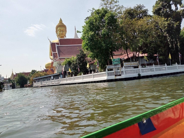 Golden Buddha statue next to a waterway.
