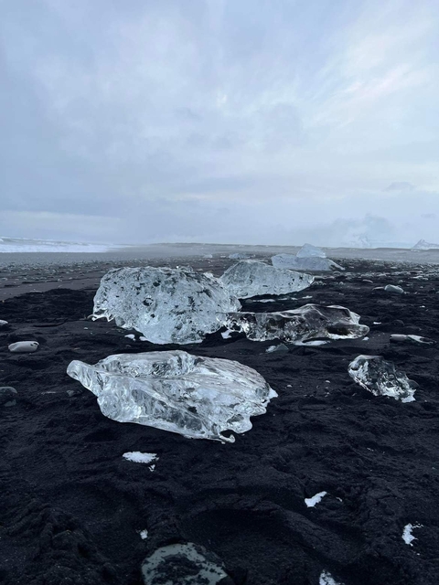 Black sand beach with scattered ice formations.