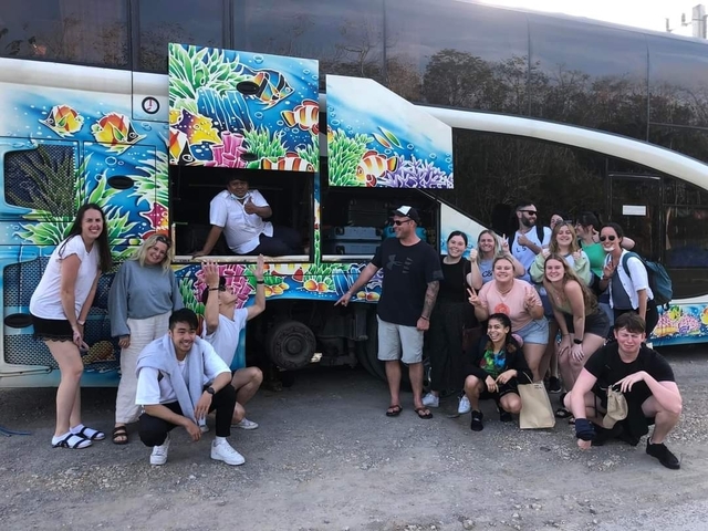 Group posing in front of a colorful bus.