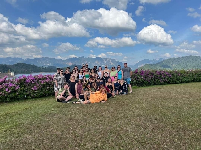 Large group with mountains and flowers in the background.