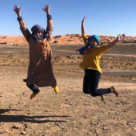       Two people joyfully jumping in a desert landscape.
  