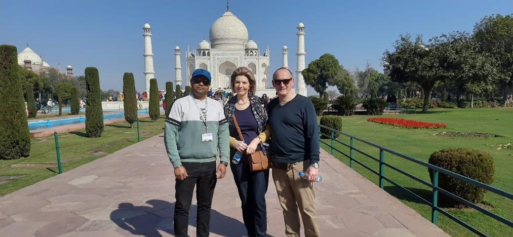       Three people posing in front of the Taj Mahal.
  