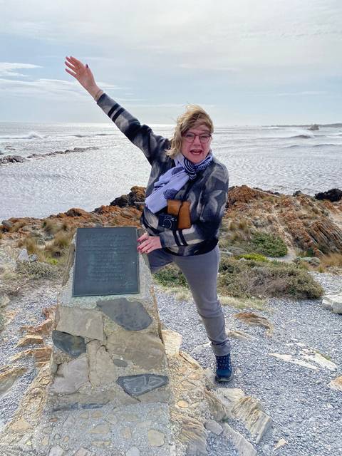 Person posing on a trail with ocean view.