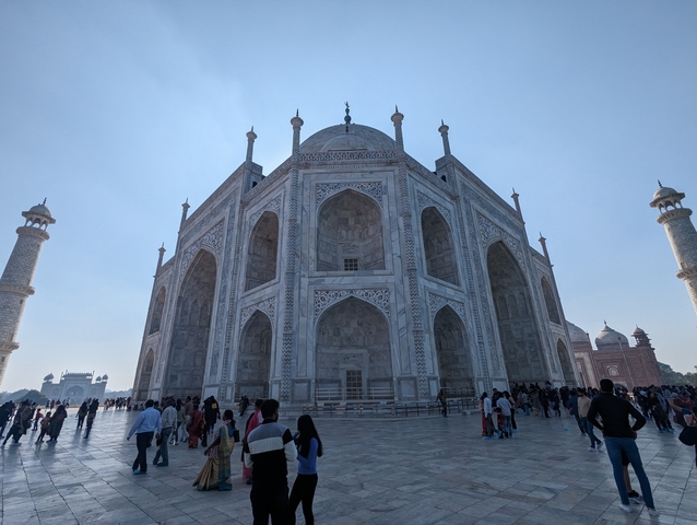       The Taj Mahal with many visitors around, seen on a bright day.
  