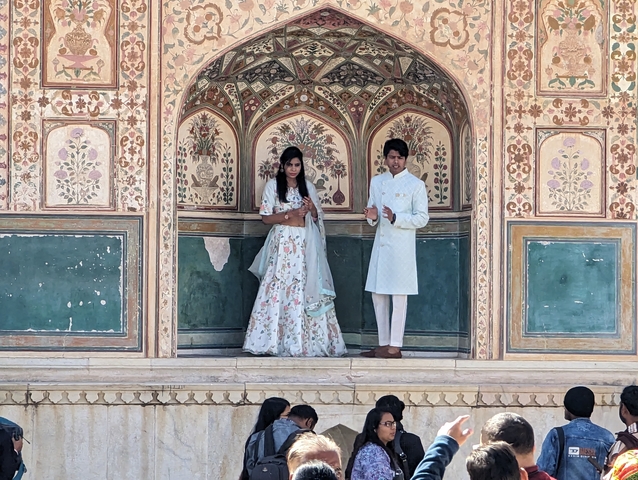       Couple posing in traditional attire in architectural backdrop.
  