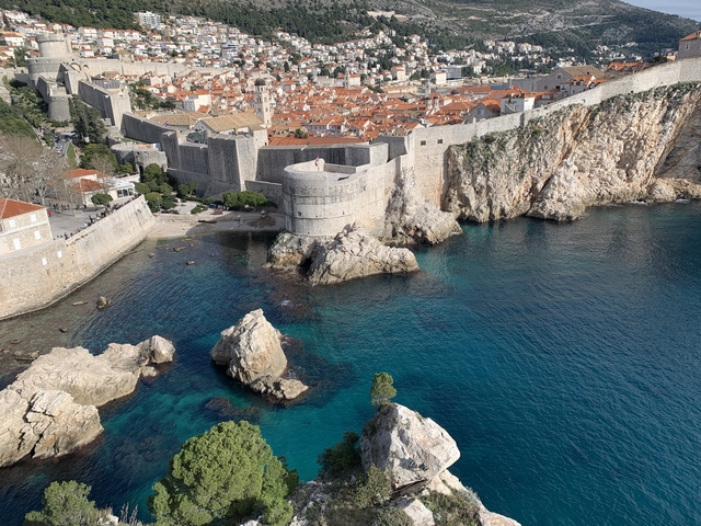       Rocky coastline with fortifications and clear water.
  