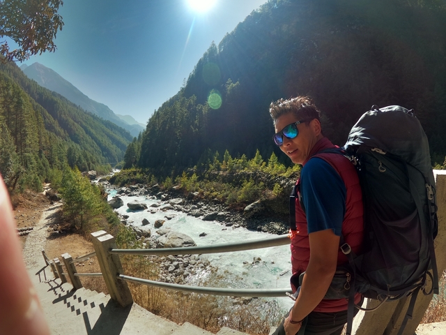 A person next to a river in a forested area.