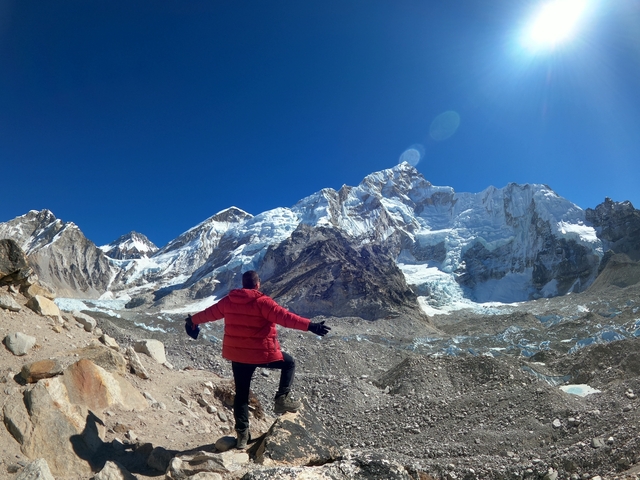 A person with arms outstretched facing snowy mountains.