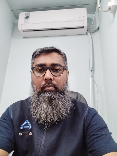       Person with beard and glasses posing indoors.
  