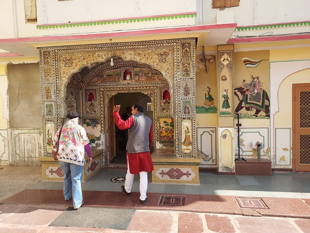       Two people observing a decorative entrance with detailed artwork.
  