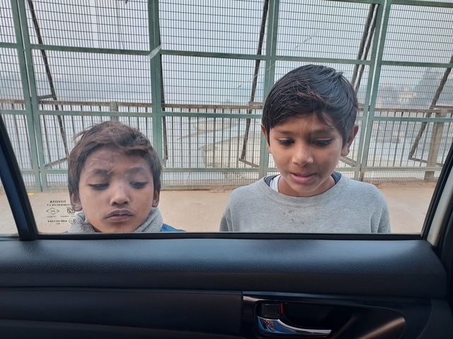       Two children looking through a glass window.
  