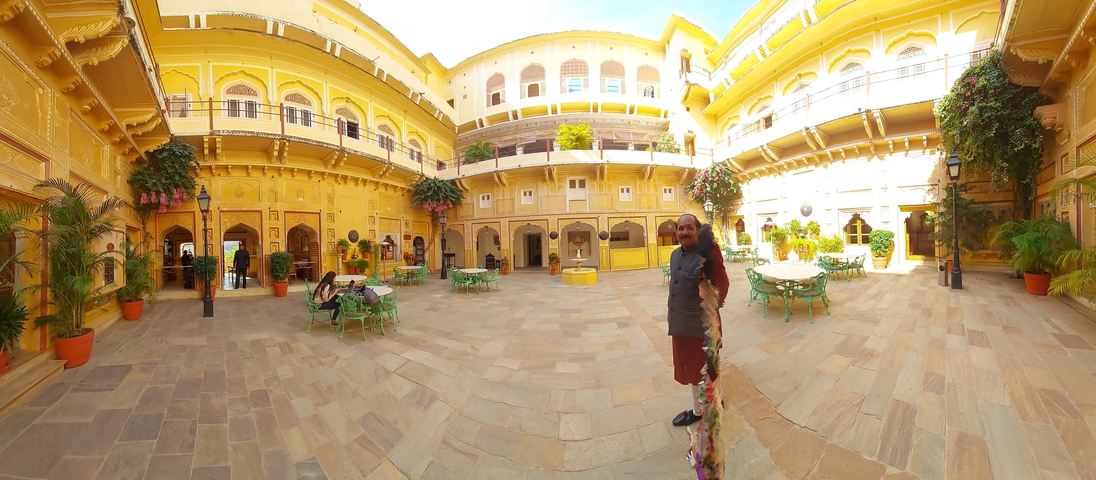       Courtyard with yellow buildings and a man standing to the right.
  