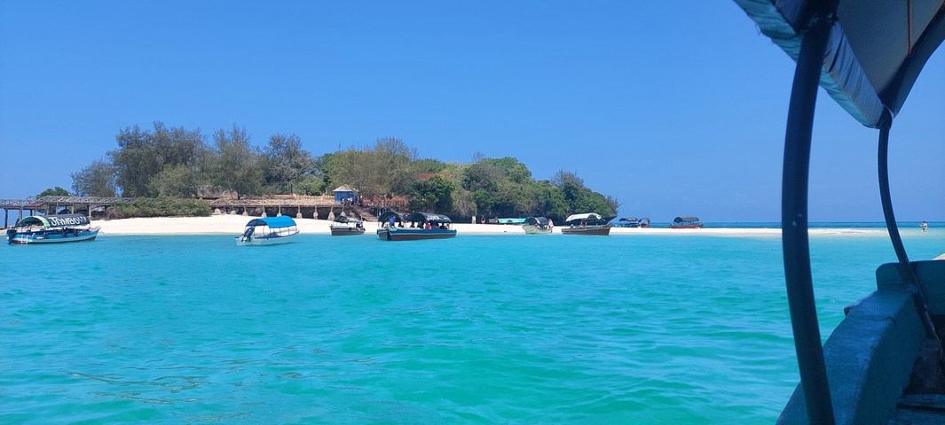 Boats anchored near a white sand beach with turquoise water.