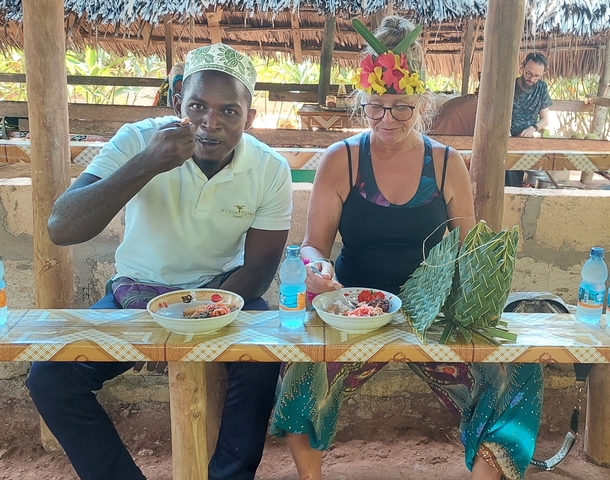 Two people eating at a wooden bench with local food and drink.