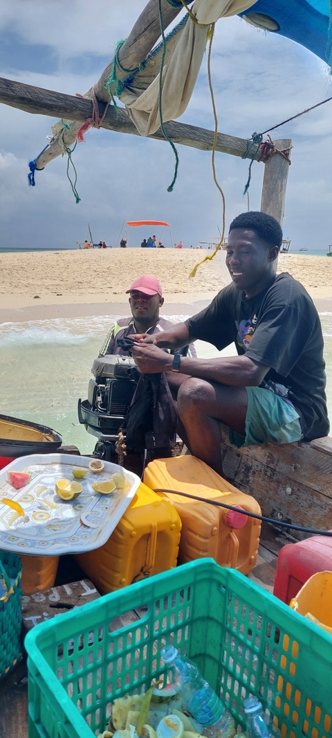 Two people near a water body working with a motor engine.