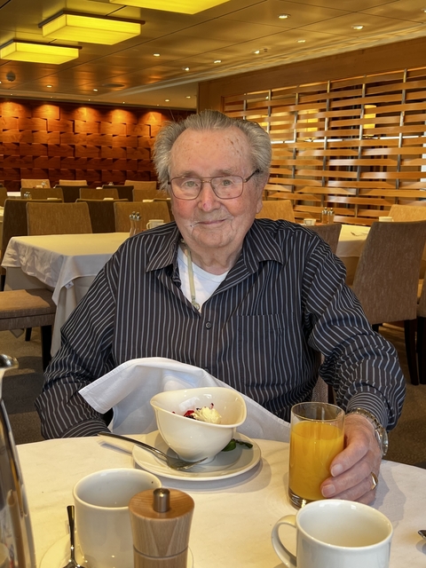 An elderly person sitting with a meal in a restaurant.