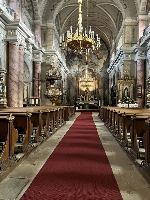 Interior of a richly decorated church with pews and an altar.