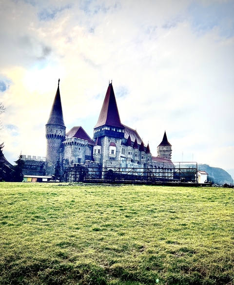 A grand medieval castle with towers and green lawns.