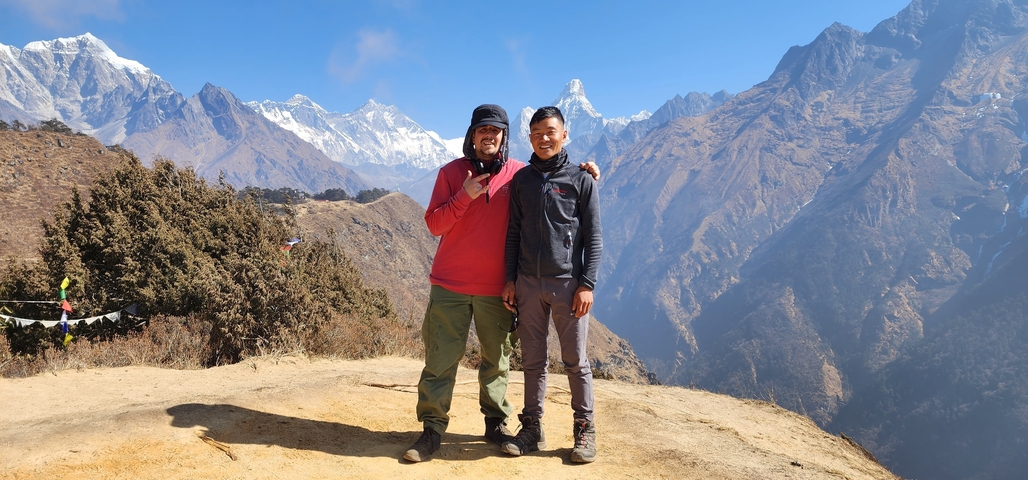       Two people posing with majestic mountains in the background.
  