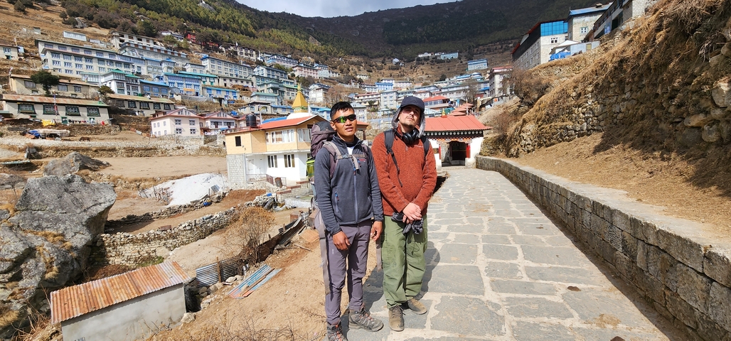 Two people standing in a mountainous village.