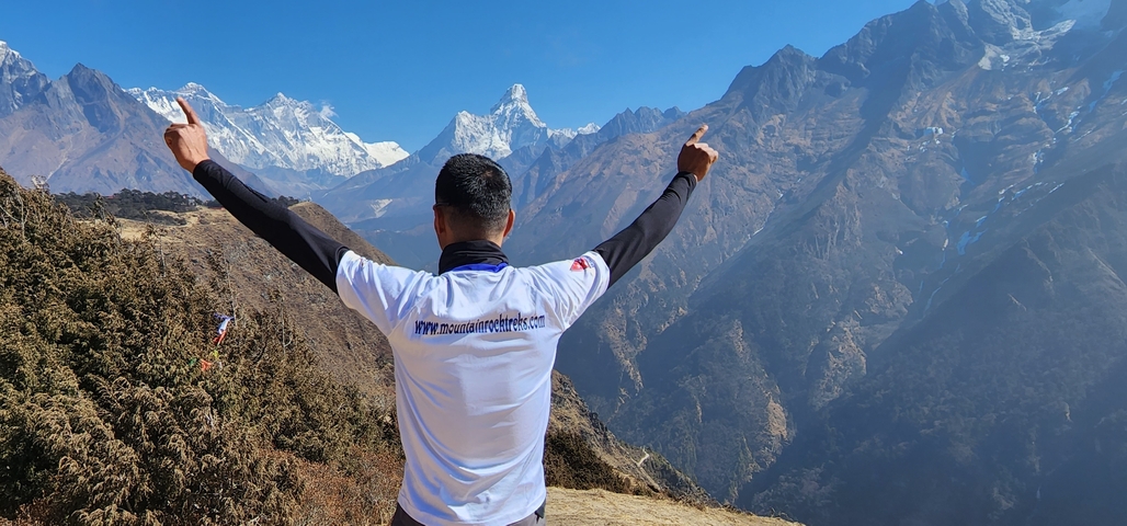 Person raising arms with mountains in the background.
