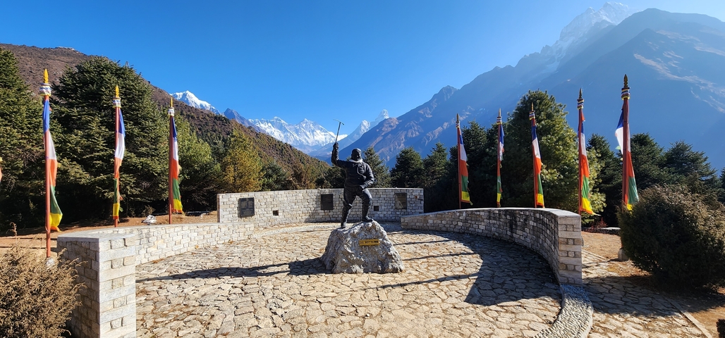 Monument with flags and snow-capped mountains.