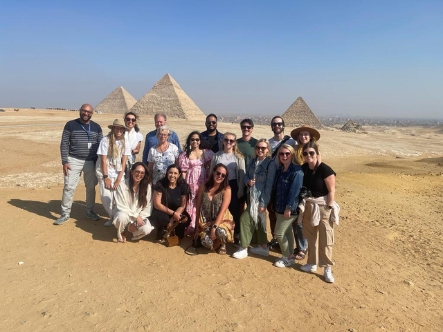 Group of people posing with the Pyramids of Giza in the background.