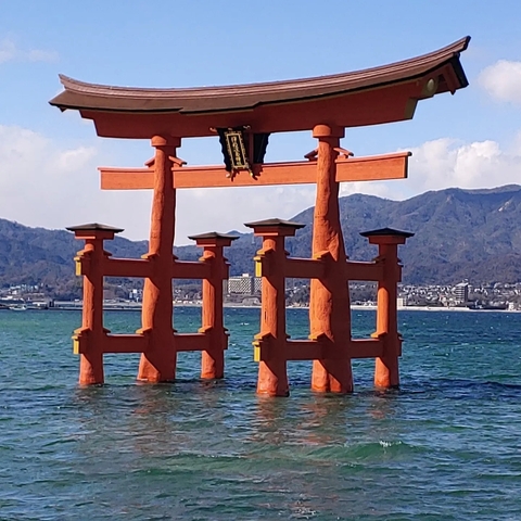 Floating torii gate in the water with mountains in the background.
