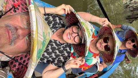 A person wearing a traditional hat and glasses, smiling close-up.
