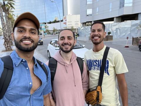 Three people smiling in front of a modern building.