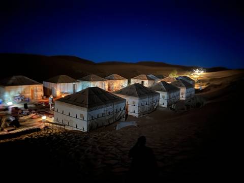 Desert camp setup at dusk with tents.