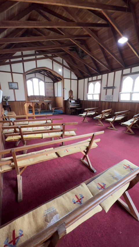 Interior of a small wooden church with benches.