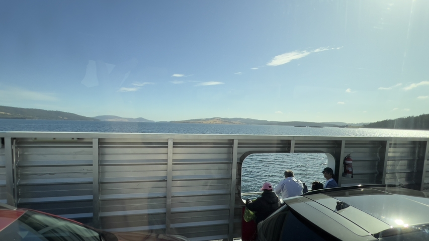 People enjoying a ferry ride with views of water and hills.