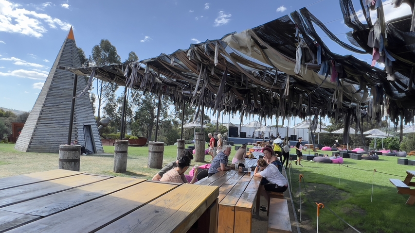 Outdoor area with people sitting under a shaded structure.