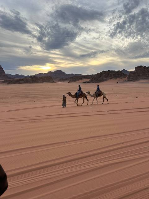 Camel riders walking through the desert.