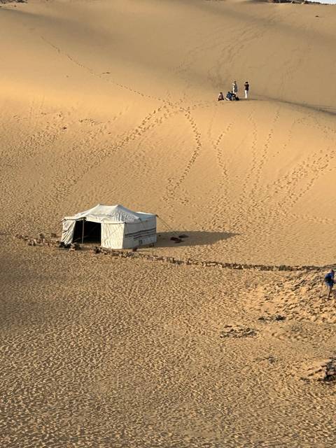       Tent pitched in the desert with footprints in the sand.
  