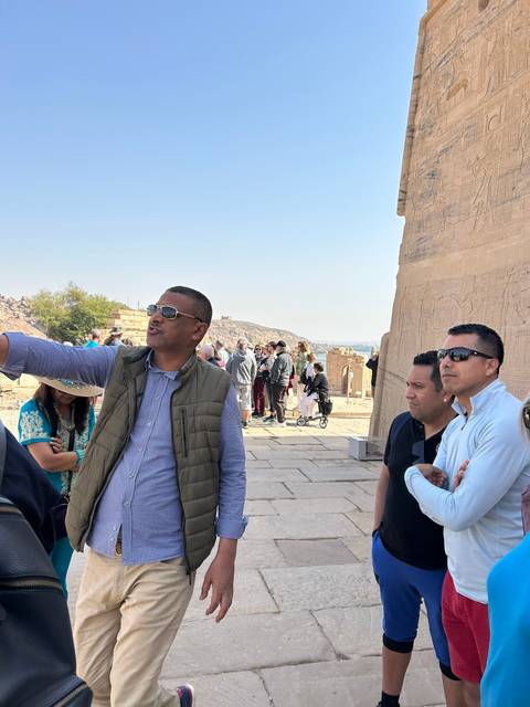 Tourists exploring ancient ruins under blue sky.