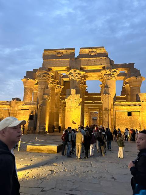 Group visiting illuminated ancient temple ruins.