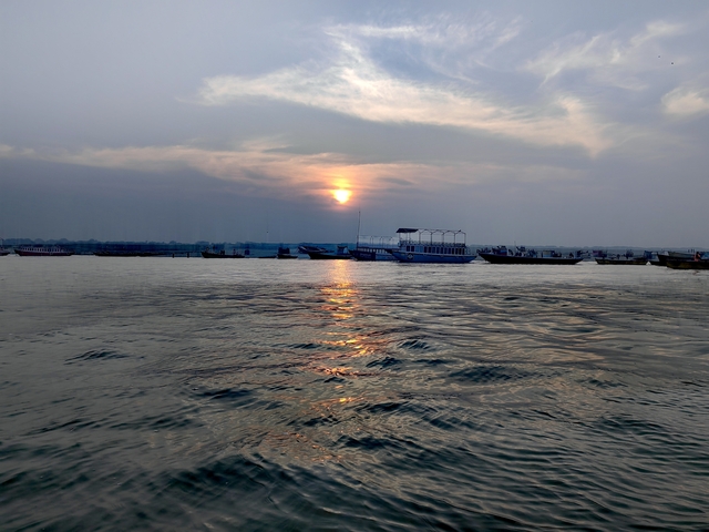 Sunset over a river with boats and a reflective water surface.